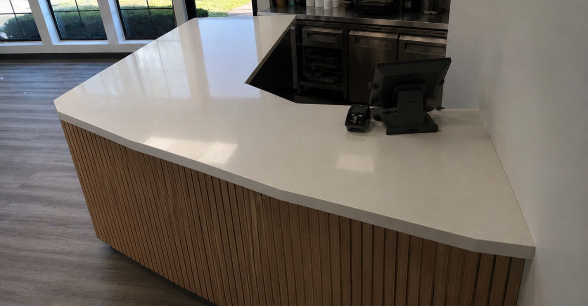 Commercial reception counter fabricated in quartz with a wood slat base
